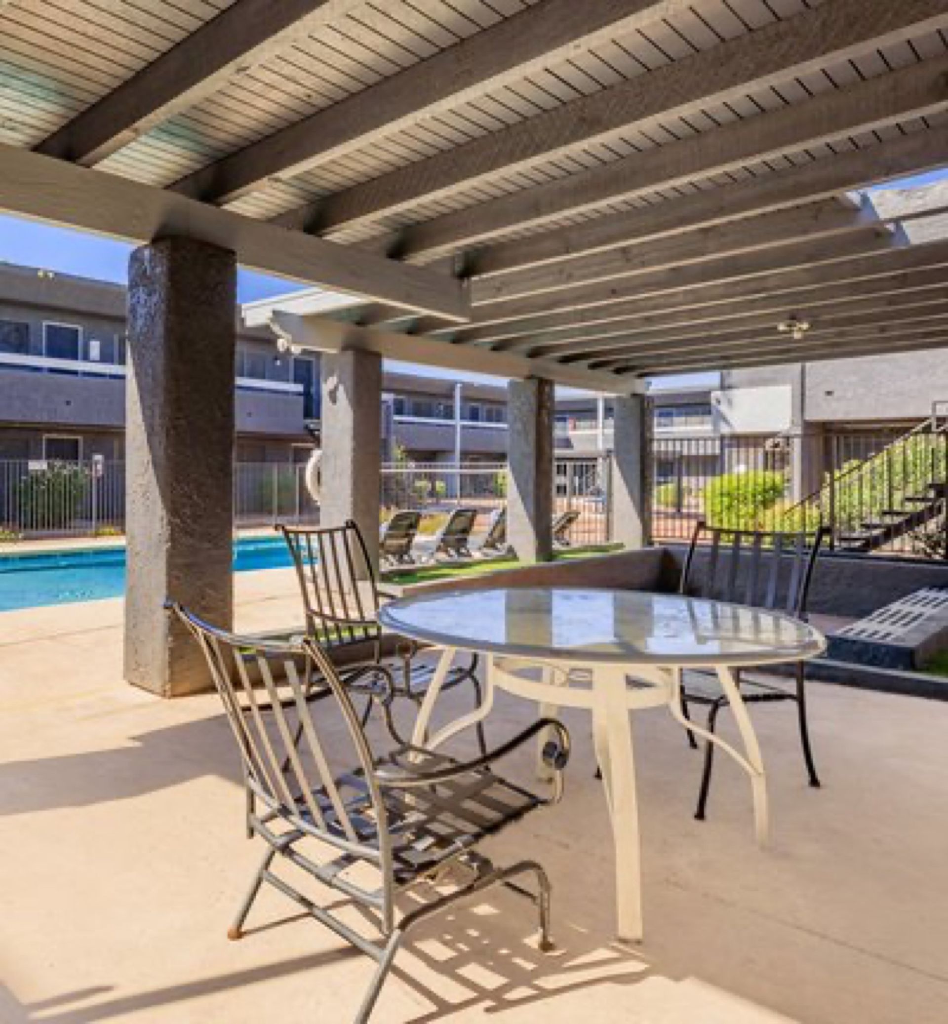 The pool deck pergola with a table and chairs